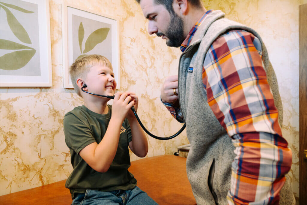 Dr. Aaron Neisen showing a pediatric patient how a stethoscope works